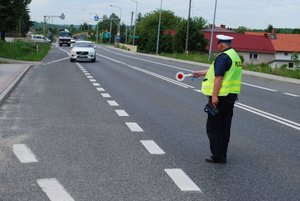 policjant dający sygnał tarczą do zatrzymywania kierującemu