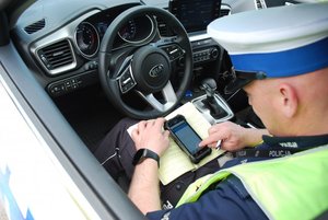 policjant w radiowozie spisujący dane do notatnika służbowego