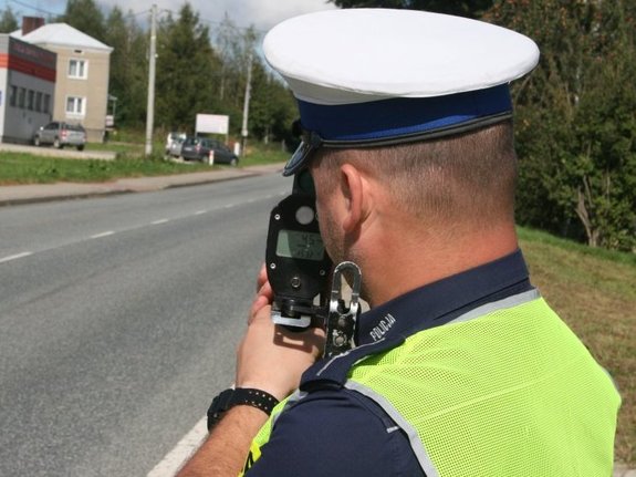 policjant ruchu drogowego wykonujący pomiar prędkości laserowym miernikiem