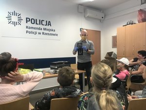 Dzieci podczas wizyty w rzeszowskiej komendzie i policjant prezentujący ślad obuwia