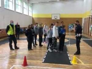 policjanci wydziału ruchu drogowego na sali gimnastycznej wraz z uczniami którzy zdają test praktyczny pokonując tor jazdy na rowerze podczas Turnieju Bezpieczeństwa Ruchu Drogowego w Powiatowym Zespole Placówek Wychowawczych w Mielcu
