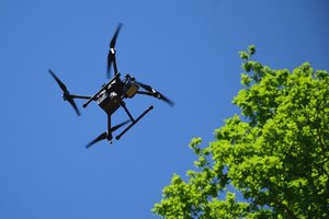 Policyjny dron w trakcie lotu na tle błękitnego nieba.