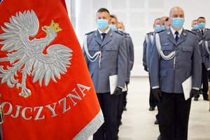 Na pierwszym planie sztandar Komendy Wojewódzkiej Policji w Rzeszowie. W dalszym planie policjanci podczas uroczystości mianowania na stopień podkomisarza Policji.