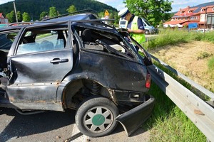 uszkodzenia pokolizyjne volkswagena, widoczne uszkodzenia tylnej części pojazdu. Na drugim planie, policjant ruchu drogowego podczas wykonywania oględzin