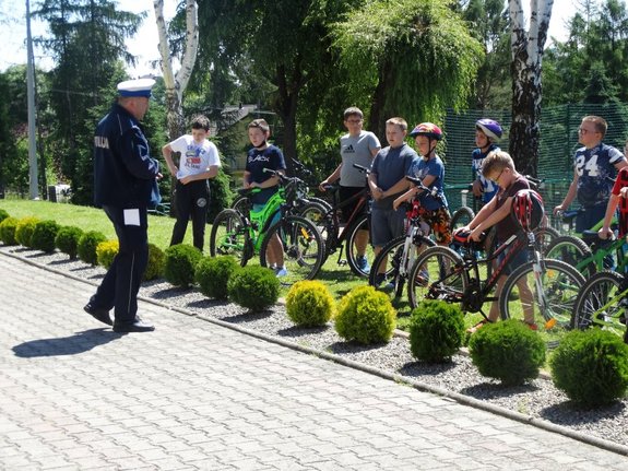 Policjant omawiający z dziećmi zasady przeprowadzenia egzaminu na kartę rowerową