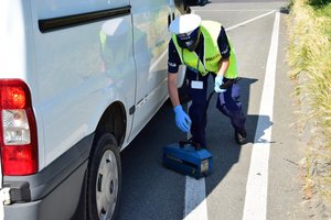 policjantka montująca dymomierz do rury wydechowej