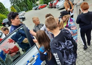 Policjantka rozmawia z dziećmi oraz prezentuje radiowóz