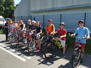 Na zdjęciu policjantka ruchu drogowego w towarzystwie uczniów zdających egzamin na kartę rowerową. Dzieci stoją obok swoich rowerów.