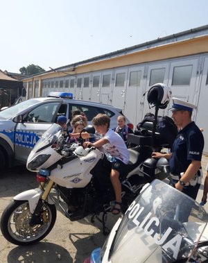 Dziecko siedzi na policyjnym motocyklu. Obok stoi policjant