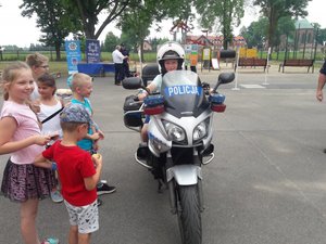 chłopiec na motorze policyjnym, obok chłopca stoją inne dzieci