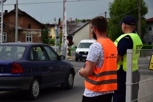Uczestnicy kampanii rozdają ulotki na przejeździe. W tle przejeżdżające samochody.