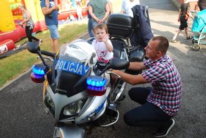 Mała dziewczynka macha rączką, siedząc na policyjnym motocyklu