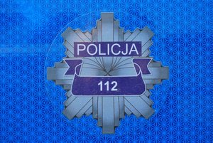 Drzwi policyjnego radiowozu z policyjną gwiazdą, na niej napis 112.