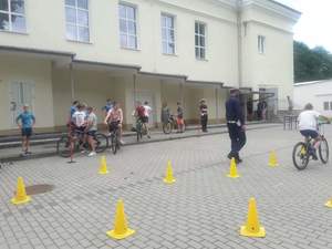 uczniowie na rowerach podczas egzaminu na kartę rowerową, na placu manewrowym widać również policjanta