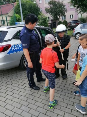 Dzieci w obecności policjantki próbują sprzęt policyjny.