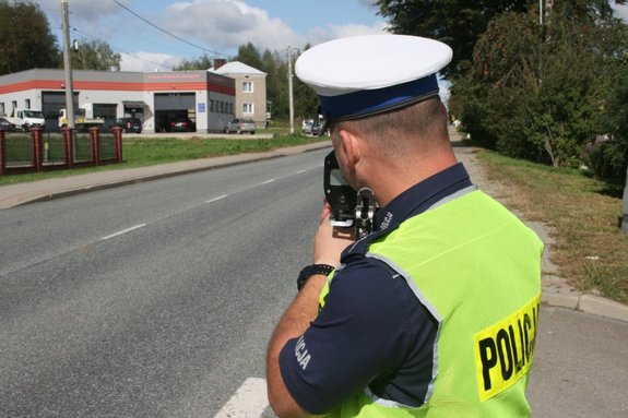 umundurowany policjant ruchu drogowego dokonuje pomiaru prędkości