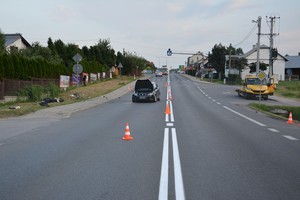 Miejsce zdarzenia na ul. Krośnieńskiej w Miejscu Piastowym. Na zdjęciu widoczny uszkodzony samochód osobowy oraz znajdujący się na pasie zieleni motocykl, obok laweta do transportu uszkodzonych pojazdów.