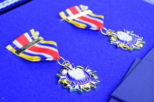 Odznaczenia leżące na niebieskim suknie.