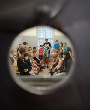 Zdjęcie kolorowe zrobione przez wizjer przedstawia grupę dzieci które przebywają w KMP w Przemyślu na spotkaniu profilaktycznym.