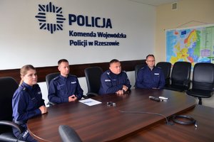 Przy stole siedzą funkcjonariusze policji, od lewej komisarz Magdalena Kruczek naczelnik Laboratorium Kryminalistycznego, biegły, który złożył ślubowanie, inspektor Piotr Zalewski zastępca Komendanta Wojewódzkiego Policji w Rzeszowie oraz funkcjonariusz laboratorium kryminalistycznego. W tle na ścianie logo Policja i napis Komenda Wojewódzka Policji w Rzeszowie