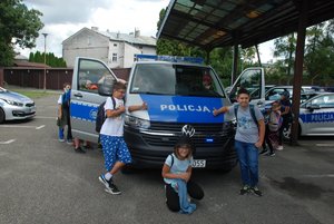 1.	Zdjęcie kolorowe przedstawia parking KMP w Przemyślu, gdzie przed oznakowanym radiowozem stoją dzieci które zwiedzają komendę.