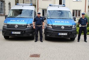 Radiowozy busy na dziedzińcu komendy miejskiej policji w Rzeszowie, obok pojazdów stoją kierowcy - policjanci ruchu drogowego.