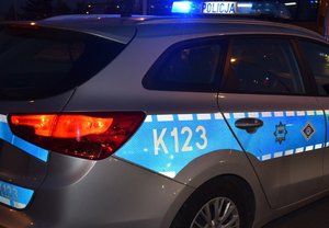 na zdjęciu zrobionym w nocy radiowóz z odblaskowymi elementami karoserii i napisem Policja