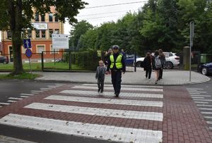 Funkcjonariusz przeprowadza chłopca przez przejście dla pieszych