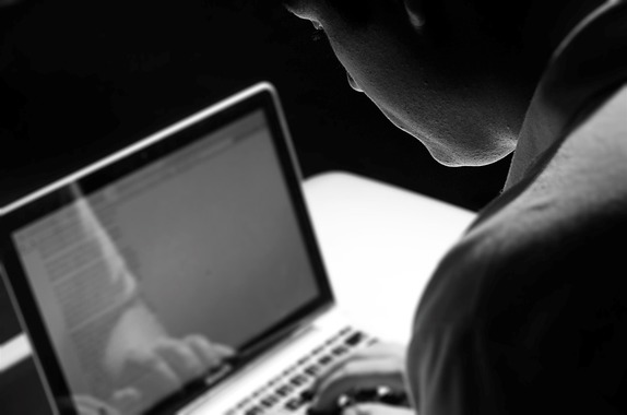 Osoba pochylona nad komputerem - pisząca na klawiaturze