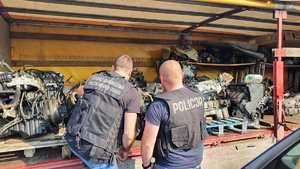 Dwóch funkcjonariuszy, przed nimi części samochodowe zabezpieczone w warsztacie na terenie gminy Majdan Królewski