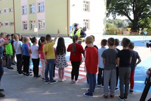 Policjant wydziału ruchu drogowego komendy wojewódzkiej w Rzeszowie podczas inauguracji projektu pn. „Bezpieczeństwo - pierwsza klasa”. Rozmawia z pierwszoklasistami ze Szkoły Podstawowej w Krzemienicy, na miasteczku ruchu drogowego.