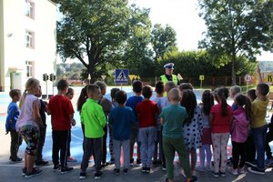 Policjant wydziału ruchu drogowego komendy wojewódzkiej w Rzeszowie podczas inauguracji projektu pn. „Bezpieczeństwo - pierwsza klasa”. Rozmawia z pierwszoklasistami ze Szkoły Podstawowej w Krzemienicy, na miasteczku ruchu drogowego.
