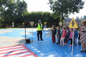 Policjant wydziału ruchu drogowego komendy wojewódzkiej w Rzeszowie podczas inauguracji projektu pn. „Bezpieczeństwo - pierwsza klasa”. Rozmawia z pierwszoklasistami ze Szkoły Podstawowej w Krzemienicy, na miasteczku ruchu drogowego.
