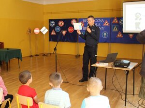Policjant wydziału ruchu drogowego komendy wojewódzkiej w Rzeszowie podczas inauguracji projektu pn. „Bezpieczeństwo - pierwsza klasa”. Rozmawia z pierwszoklasistami ze Szkoły Podstawowej w Krzemienicy, na miasteczku ruchu drogowego.