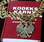 Na zdjęciu leży książka- kodeks karny, na niej widzimy sędziowski łańcuch z godłem Polski