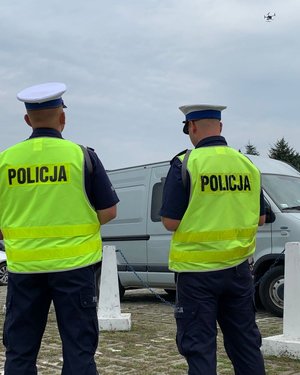 Policjanci monitorowali sytuację na przejeździe kolejowym, na ul. Hanasiewicza w Rzeszowie. Dwóch policjantów obsługujących policyjnego drona. W tle nieoznakowany radiowóz