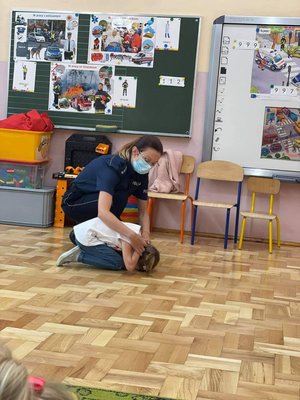Policjantka pokazująca dziecku jaka należy przybrać pozycje, gdy zaatakuje pies