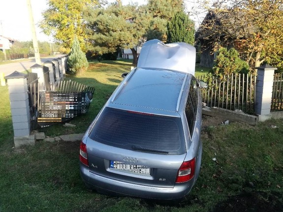 Pojazd marki Audi stojący pośrodku ogrodzenia. Obok niego wyłamane przęsła płotu.