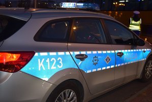 nocne zdjęcie radiowozu, jasne elementy odblaskowe i napis policja