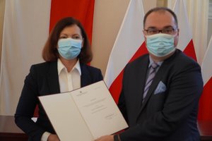 Wojewoda Ewa Leniart oraz prof. Czesław Kłak prezentują dokument porozumienia. W tle biało-czerwone flagi