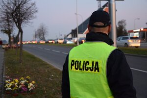 policjant stojący przy drodze w rejonie cmentarza