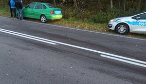 Zdjęcie kolorowe  wykonane w prze dziennej przedstawia pojazd volkswagen polo w kolorze zielonym zaparkowany na poboczu drogi wojewódzkiej nr 884 w miejscowości Krzywcza. Tuz za pojazdem zaparkowany jest pojazd policyjny oznakowany.