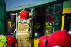 Zbliżenie na autobus - strażacy w środku i na zewnątrz udzielają pomocy poszkodowanym
