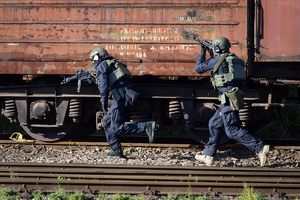 Policyjni kontrterroryści z bronią biegną wzdłuż wagonu