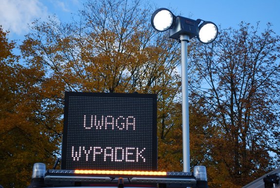Na zdjęciu tablica świetlna zamontowana na dachu radiowozu wyświetlająca ostrzeżenie &amp;quot;UWAGA WYPADEK&amp;quot;.