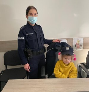 Policjantka z dziewczynką na siedząca przy stole w pokoju służbowym