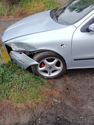 Zdjęcie kolorowe wykonane porze dziennej przedstawia pojazd marki seat koloru srebrnego który brał udział w kolizji . Pojazd ma uszkodzenia z z przodu z  lewej strony od kierowcy