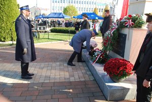 Komendant Powiatowy Policji w Ropczycach składający wiązankę kwiatów przed pomnikiem