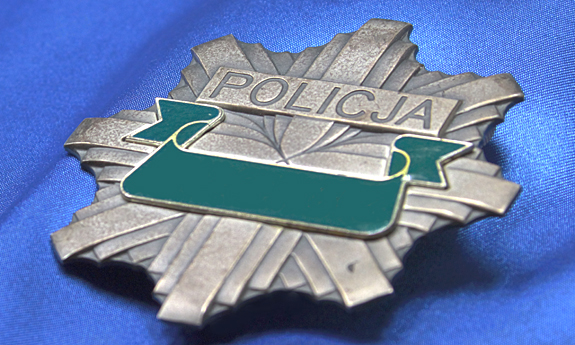 zdjęcie przedstawiająca odznakę policyjną z zamazanymi numerami identyfikacyjnymi funkcjonariusza, u góry odznaki napis Policja
