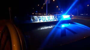 Pora nocna, na zdjęciu rozświetlona belka radiowozu, w tle rozmazane samochody